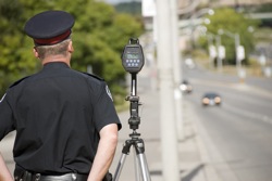 A policeman waits to catch speeding drivers with a radar gun
