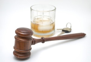 A courtroom gavel with a background of highball glass